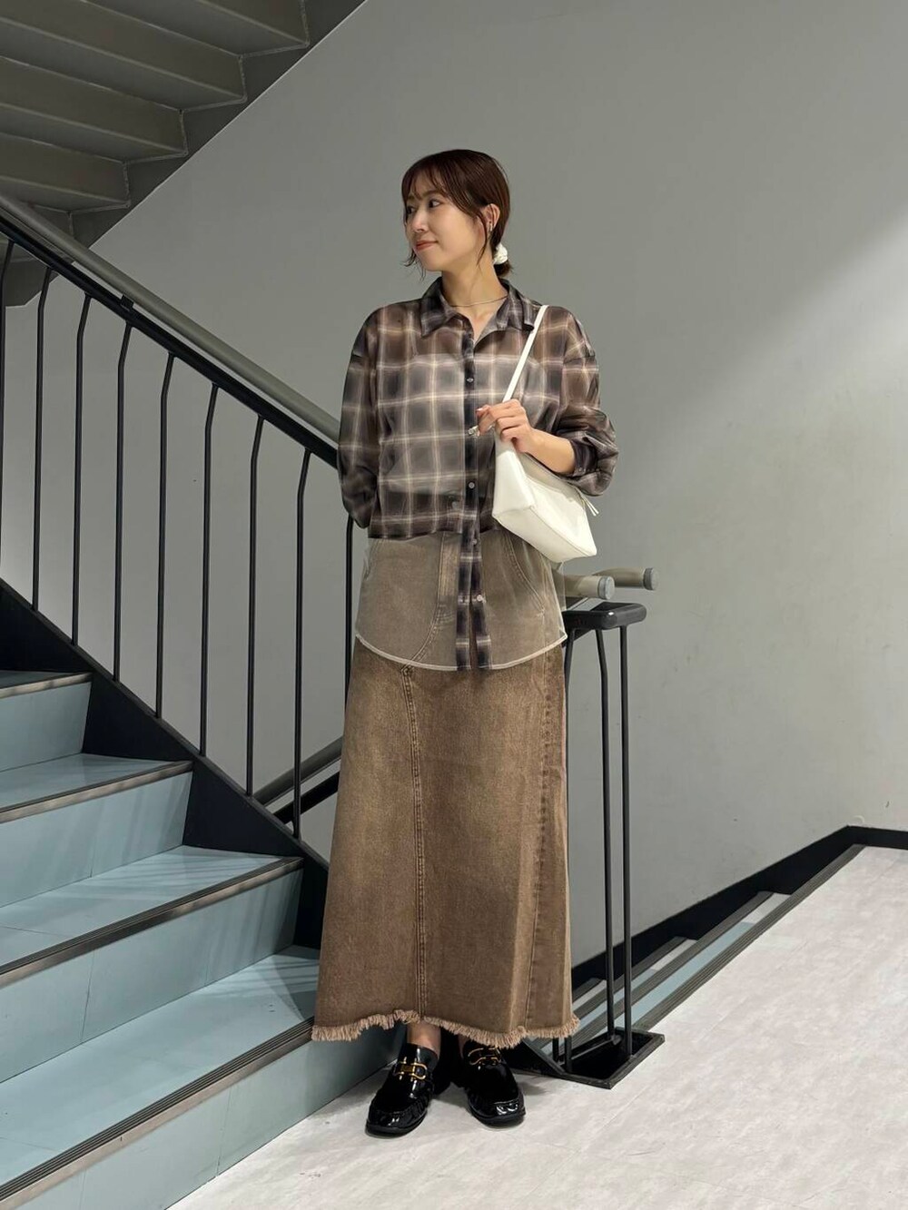 ホワイト系のショルダーバッグ、ブラウン系のスカート、ブラック系のローファーを着用したレディースの夏コーディネートの2枚目の写真