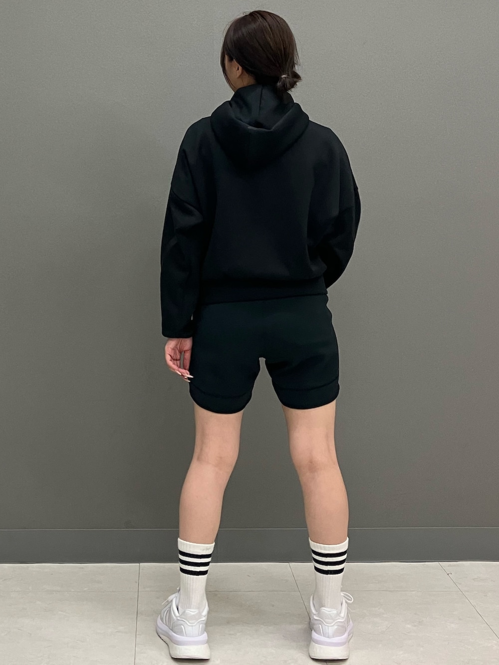 ブラック系のパーカー、ブラック系のパンツ、ホワイト系のスニーカーを着用したレディースの秋コーディネートの3枚目の写真