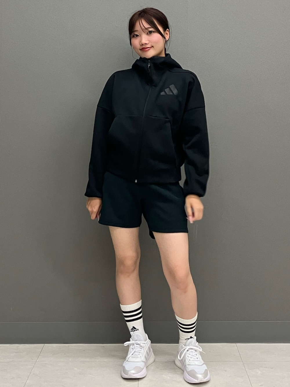 ブラック系のパーカー、ブラック系のパンツ、ホワイト系のスニーカーを着用したレディースの秋コーディネートの2枚目の写真