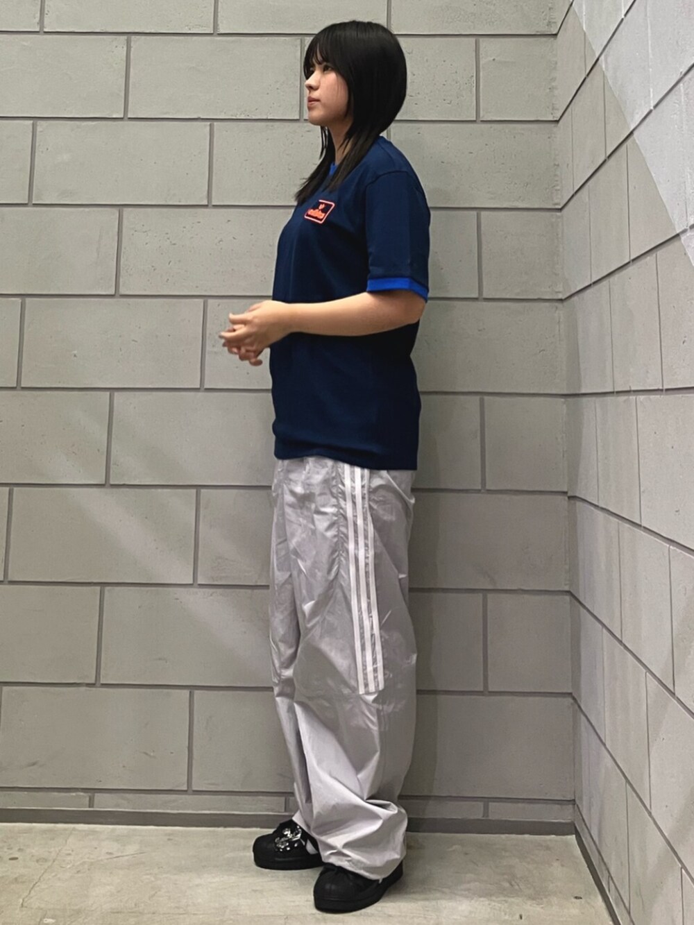 グレー系のその他パンツ、ブルー系のTシャツ/カットソー、ブラック系のスニーカーを着用したレディースの春コーディネートの2枚目の写真