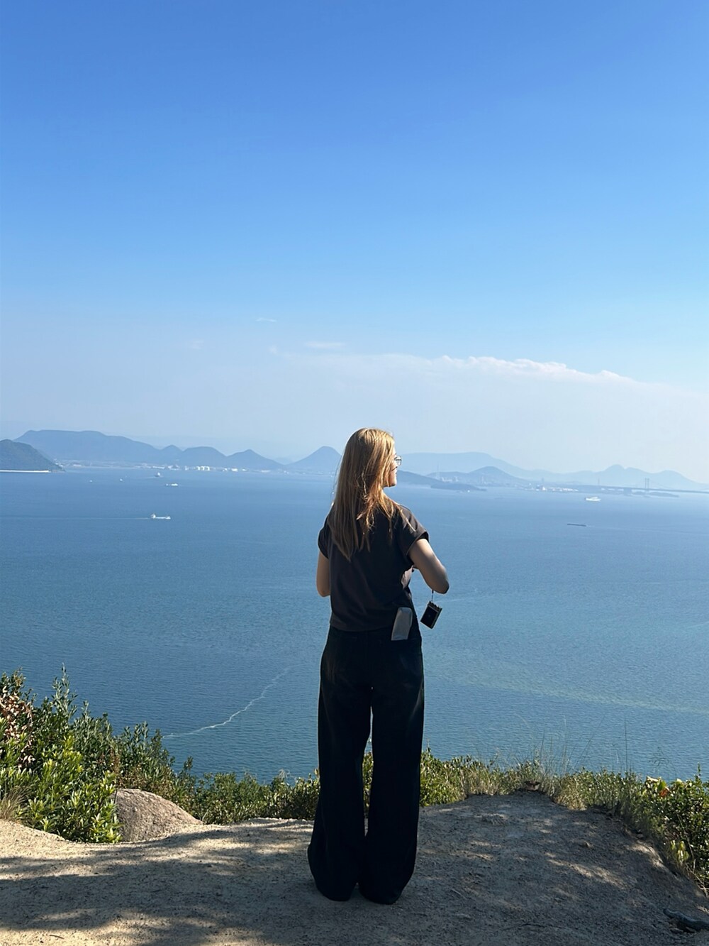 グレー系のTシャツ/カットソー、ブラック系のデニムパンツ、ベージュ系のスニーカーを着用したレディースの秋コーディネートの3枚目の写真