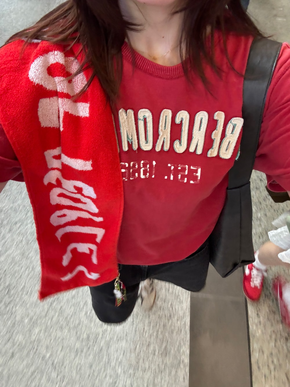 レッド系のTシャツ/カットソー、ブラック系のデニムパンツ、ホワイト系のスニーカーを着用したレディースの秋コーディネートの3枚目の写真