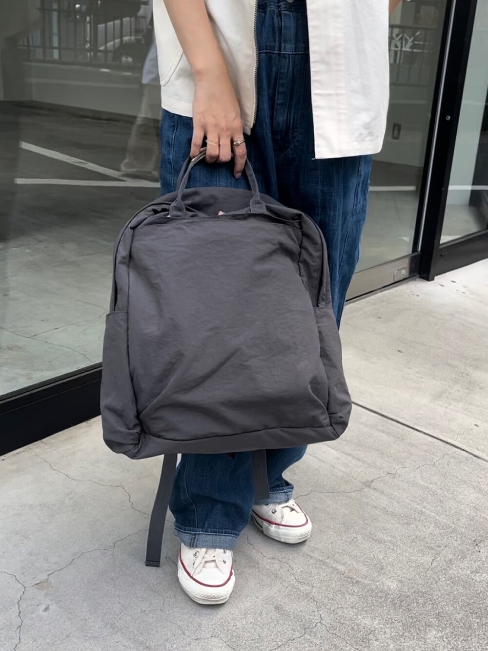 グレー系のバックパック/リュック、ブルー系のパンツ、ホワイト系のスニーカーを着用したレディースの夏コーディネートの3枚目の写真