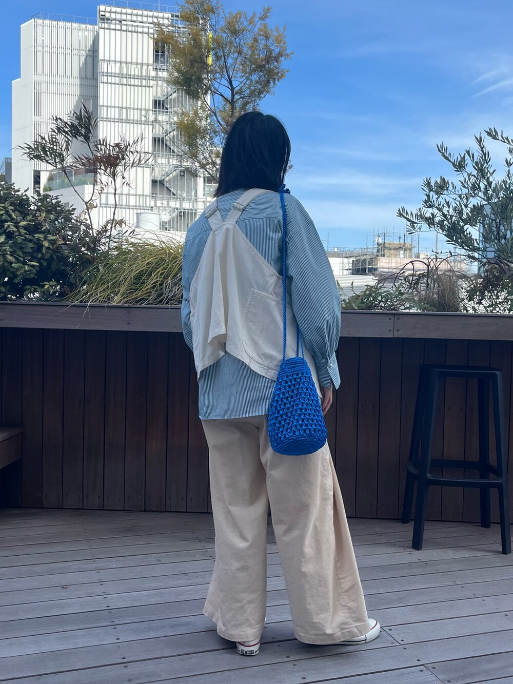 ブルー系のショルダーバッグ、ホワイト系のスニーカー、ホワイト系のベストを着用したレディースの冬コーディネートの2枚目の写真