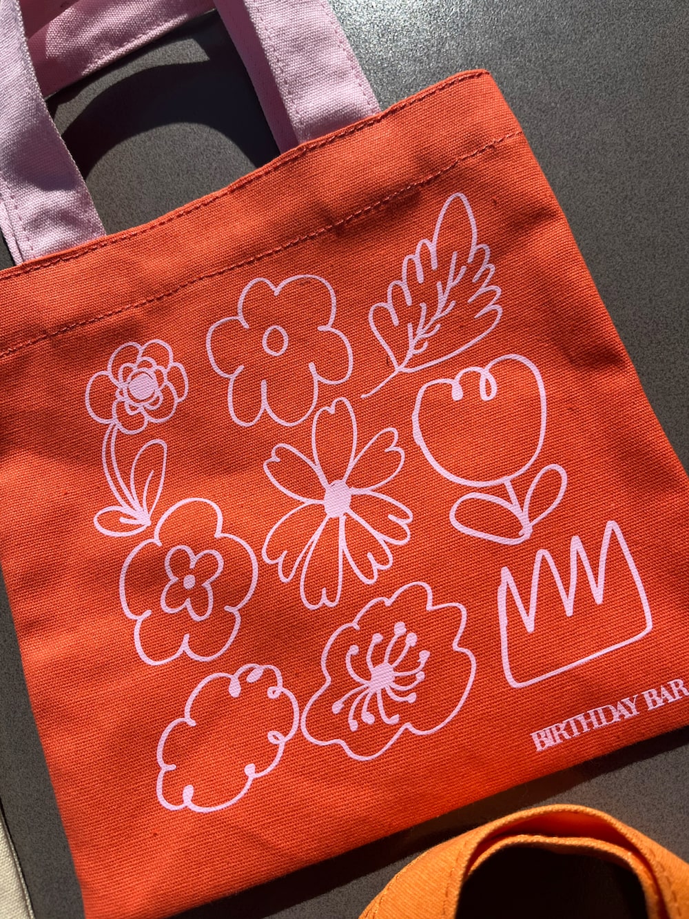 オレンジ系のトートバッグ、ピンク系のチャームを着用したレディースの春コーディネートの4枚目の写真