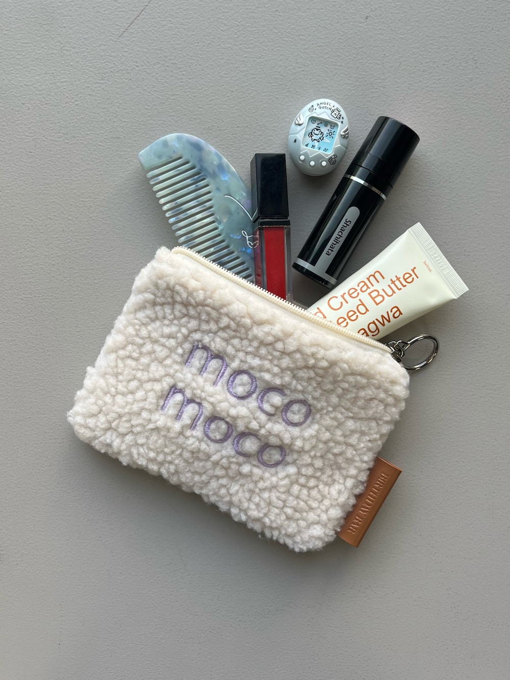 ホワイト系のポーチ、シルバー系の財布、イエロー系のインテリア雑貨を着用したレディースの冬コーディネートの2枚目の写真