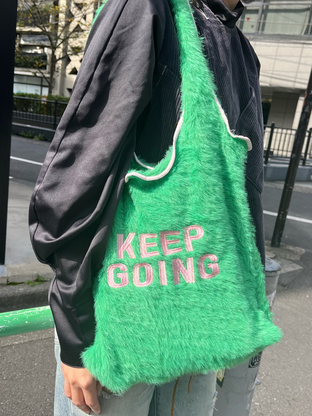 グリーン系のトートバッグ、ブルー系のデニムパンツ、グリーン系のソックス/靴下を着用したレディースの秋コーディネートの3枚目の写真