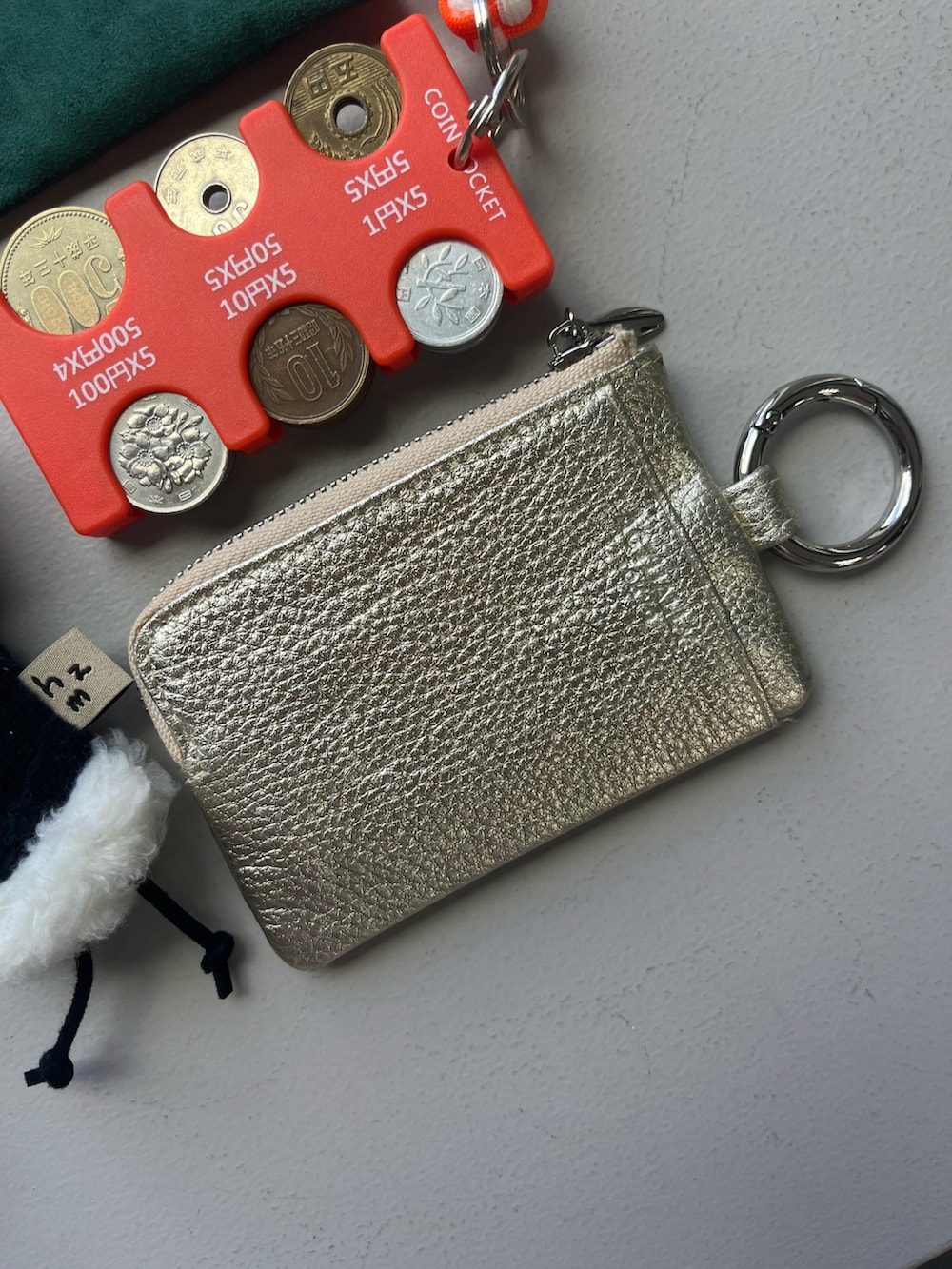 その他のハンドケア/ハンドクリーム、ゴールド系のパスケース、ホワイト系のチャームを着用したレディースの秋コーディネートの4枚目の写真