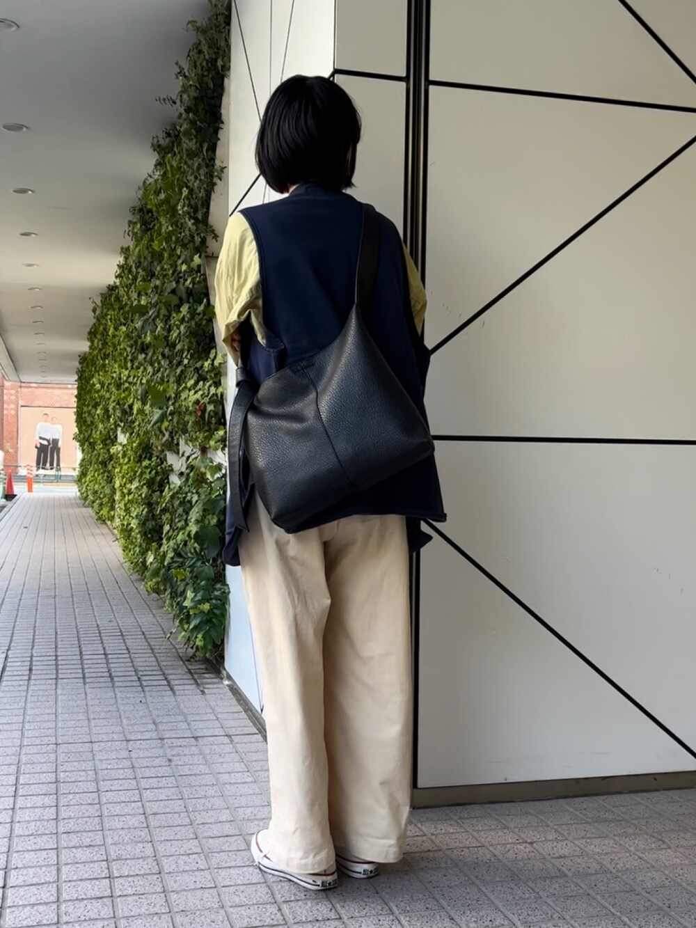 ブラック系のショルダーバッグ、ホワイト系のスニーカーを着用したレディースの秋コーディネートの2枚目の写真