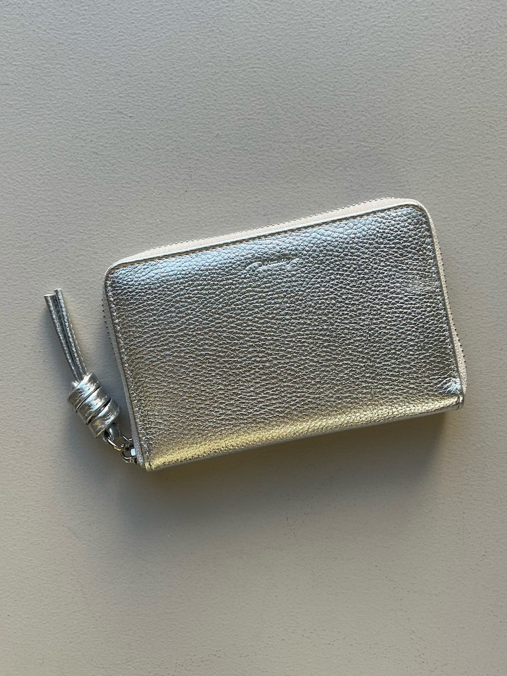 シルバー系の財布、ホワイト系の香水、ブルー系のチャームを着用したレディースの冬コーディネートの2枚目の写真