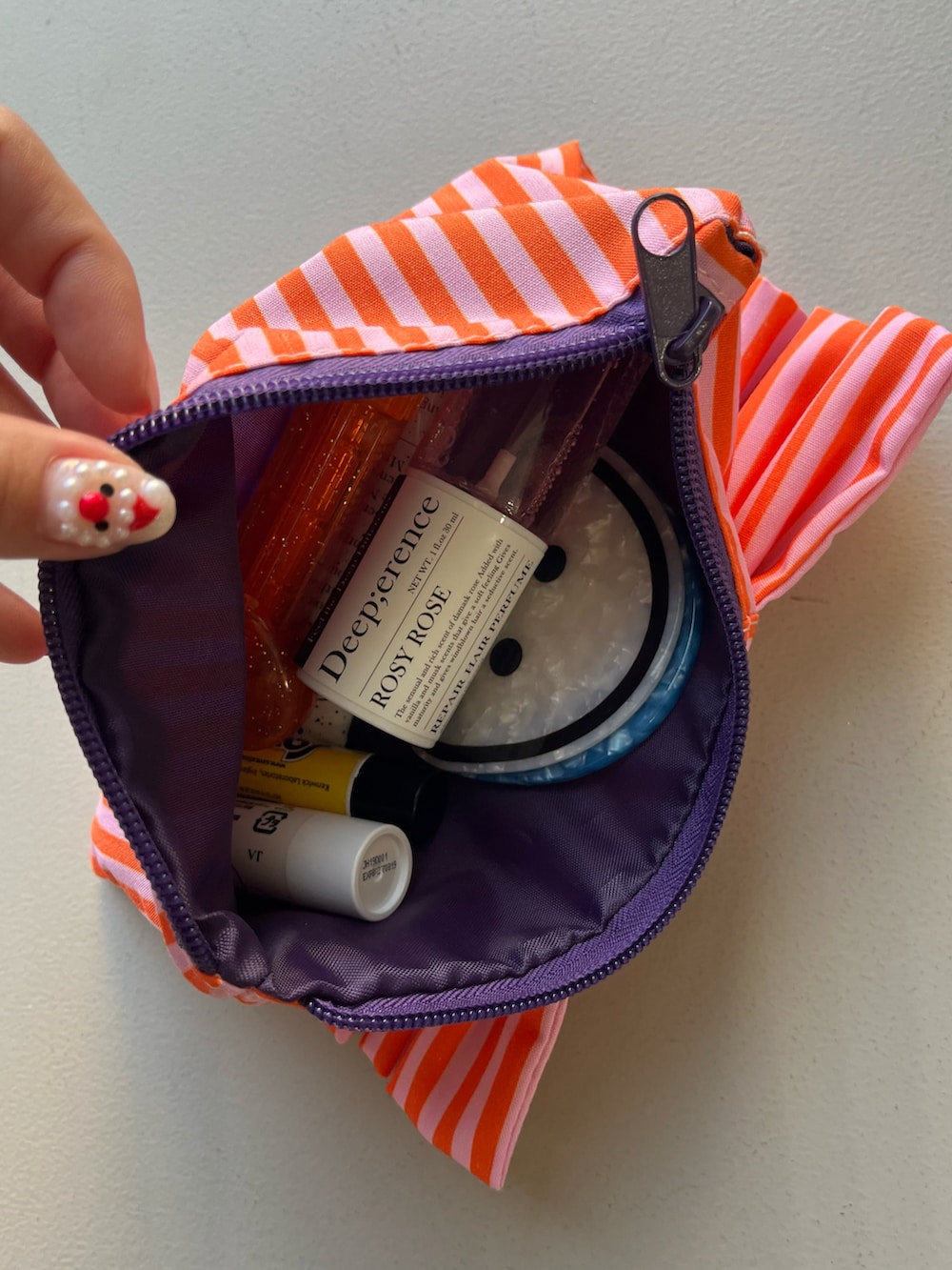 ピンク系のポーチ、イエロー系のパスケース、グリーン系のハンドケア/ハンドクリームを着用したレディースの春コーディネートの3枚目の写真