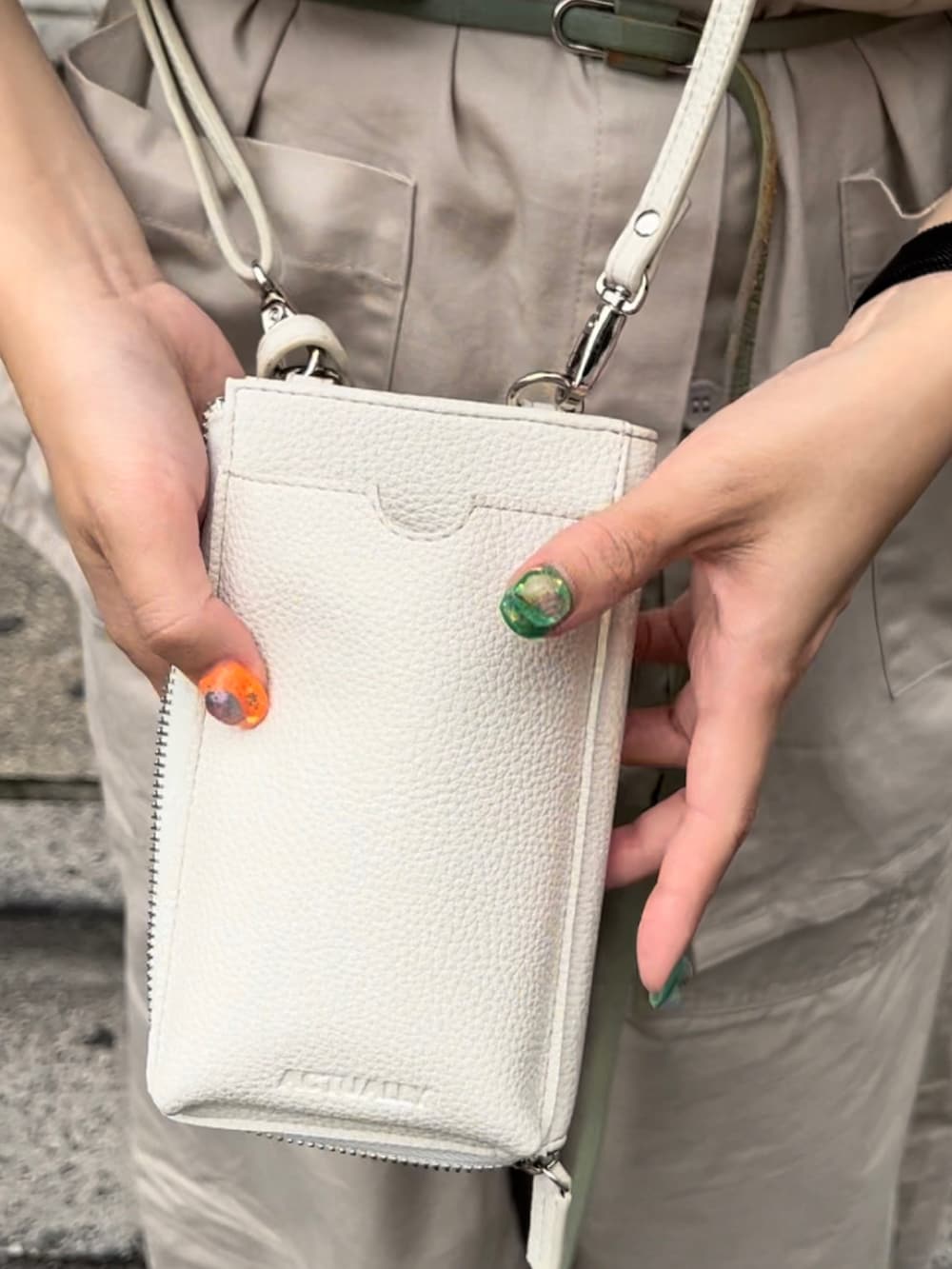 ホワイト系のショルダーバッグ、ベージュ系のスカート、ホワイト系のスニーカーを着用したレディースの夏コーディネートの3枚目の写真