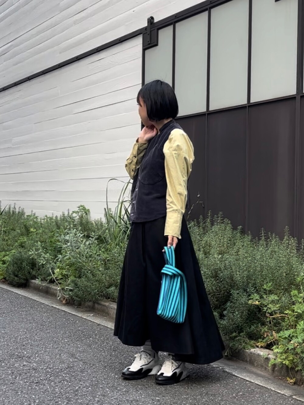 ブルー系のハンドバッグ、ホワイト系のスニーカー、ブラック系のスカートを着用したレディースの秋コーディネートの2枚目の写真