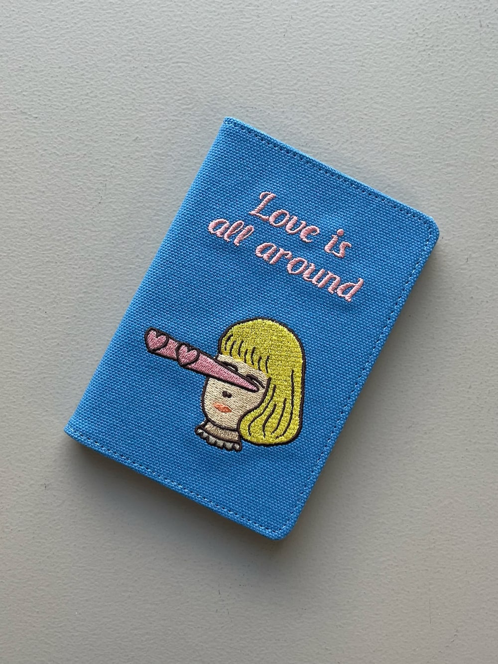 シルバー系のエコバッグ/サブバッグ、ブルー系のパスポートケース、グリーン系の財布を着用したレディースの夏コーディネートの2枚目の写真