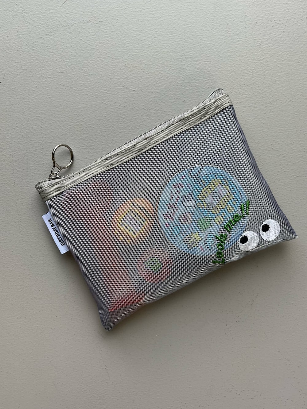 ブラック系のスマホグッズ、ゴールド系のパスケース、ピンク系の香水を着用したレディースの冬コーディネートの2枚目の写真