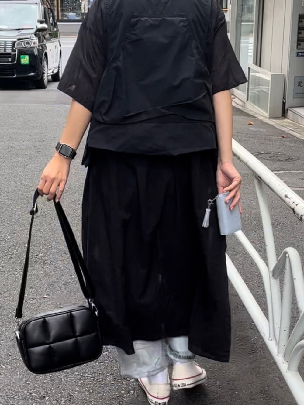 ブラック系のショルダーバッグ、ホワイト系のスニーカー、ブラック系のベストを着用したレディースの秋コーディネートの2枚目の写真