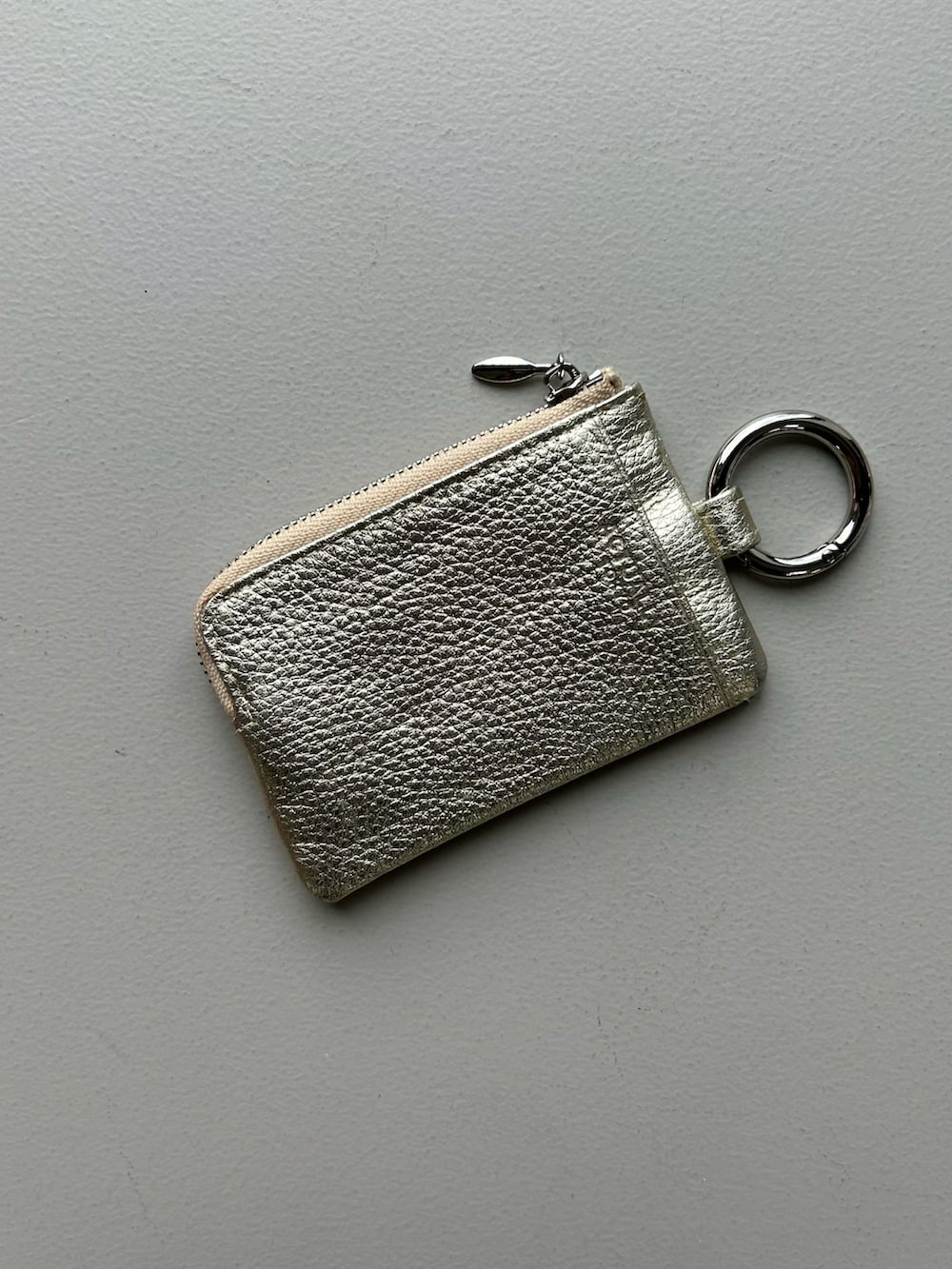 オレンジ系のポーチ、ゴールド系のパスケース、ブルー系のチャームを着用したレディースの春コーディネートの5枚目の写真