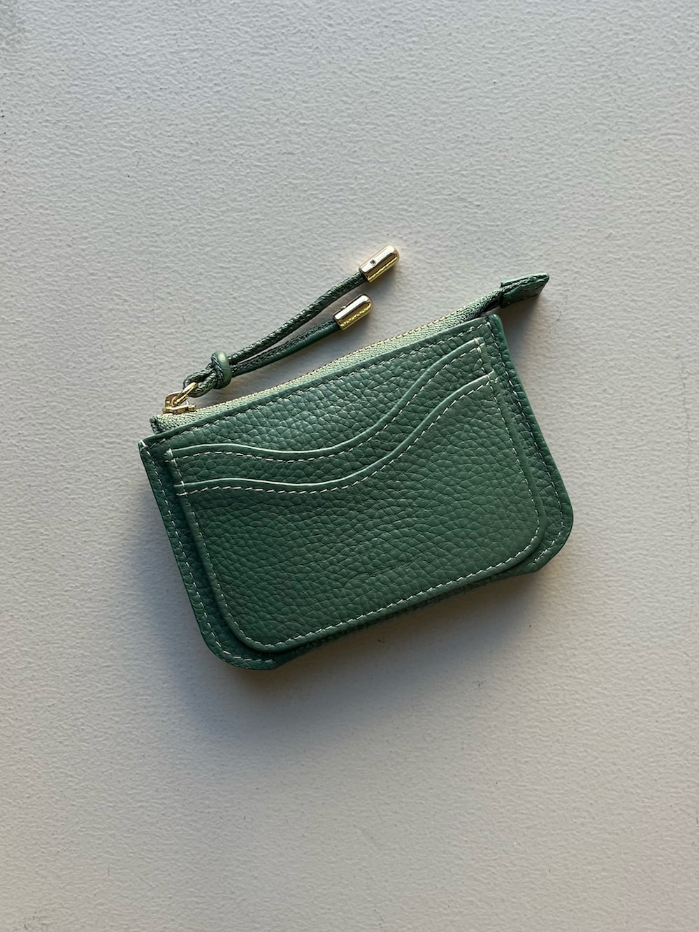 グリーン系の財布、ブラック系のポーチ、ブラック系の水筒を着用したレディースの秋コーディネートの2枚目の写真