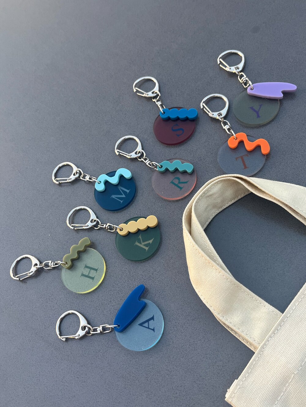 ホワイト系のトートバッグ、ブラック系のチャーム、グレー系のチャームを着用したレディースの春コーディネートの2枚目の写真