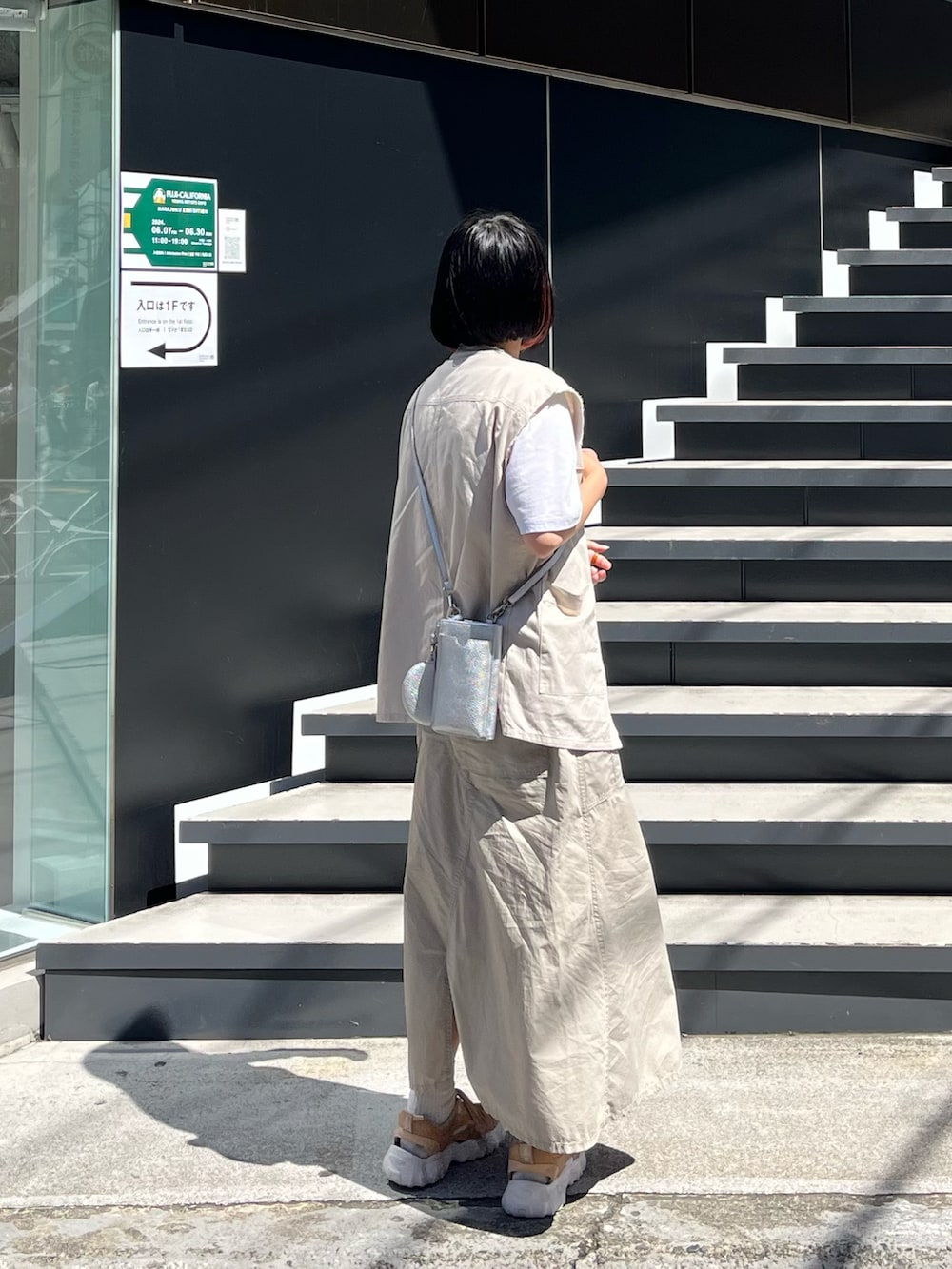 ベージュ系のスニーカー、シルバー系のショルダーバッグ、ベージュ系のスカートを着用したレディースの夏コーディネートの2枚目の写真