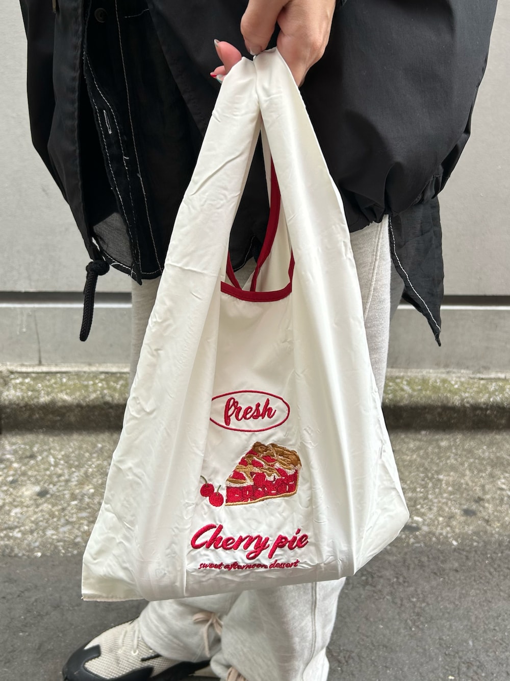 ホワイト系のエコバッグ/サブバッグ、グリーン系の財布、レッド系のポーチを着用したレディースの春コーディネートの2枚目の写真