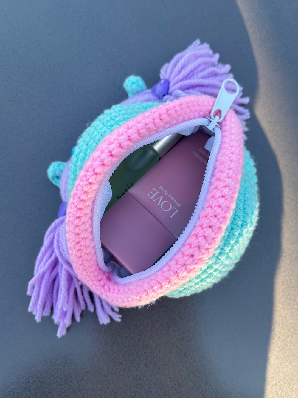 イエロー系のコインケース、パープル系のポーチ、グレー系のヘッドフォン/イヤホンを着用したレディースの冬コーディネートの3枚目の写真