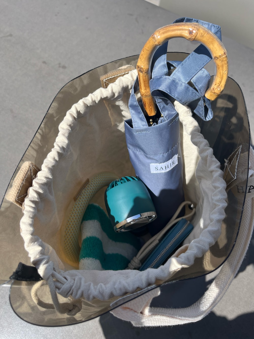 ブラック系のトートバッグ、ブルー系の財布、ブルー系の長傘を着用したレディースの春コーディネートの3枚目の写真