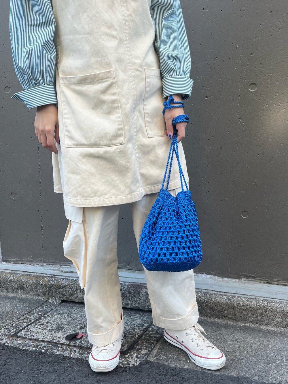 ブルー系のショルダーバッグ、ホワイト系のベスト、グリーン系のシャツ/ブラウスを着用したレディースの春コーディネートの2枚目の写真