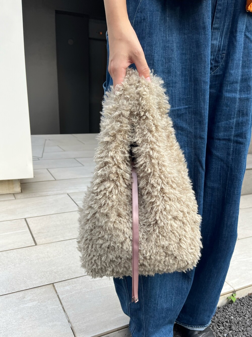 ベージュ系のトートバッグ、ブラック系のドレスシューズ、オレンジ系のカーディガン/ボレロを着用したレディースの秋コーディネートの2枚目の写真