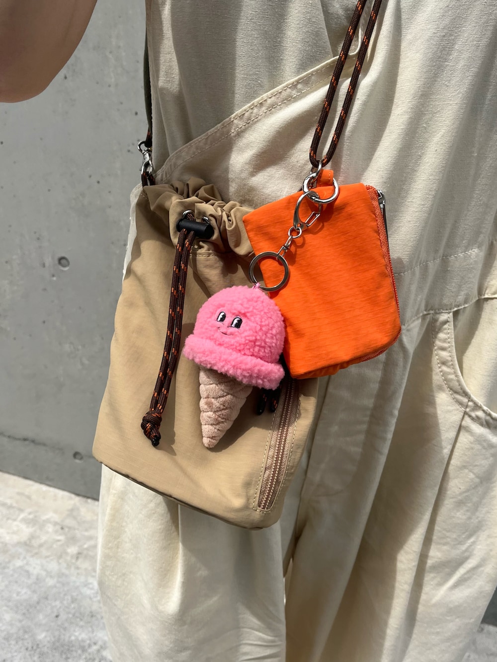 ホワイト系のスニーカー、ベージュ系のショルダーバッグ、ピンク系のチャームを着用したレディースの夏コーディネートの2枚目の写真