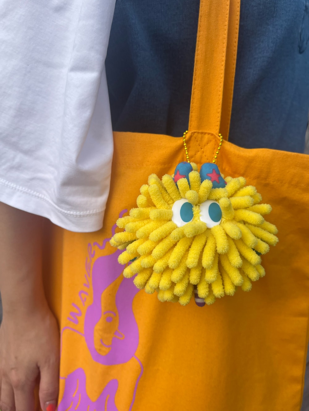 ブルー系のスカート、オレンジ系のトートバッグ、イエロー系のチャームを着用したレディースの冬コーディネートの2枚目の写真