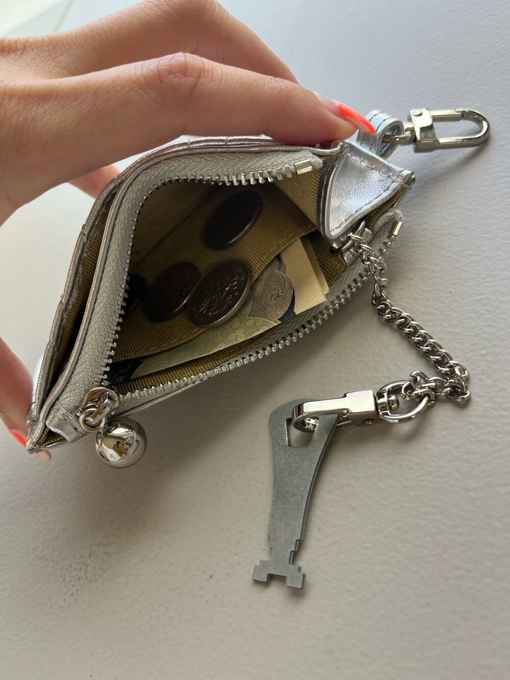 ホワイト系のスニーカー、シルバー系の財布、シルバー系のパスケースを着用したレディースの春コーディネートの2枚目の写真