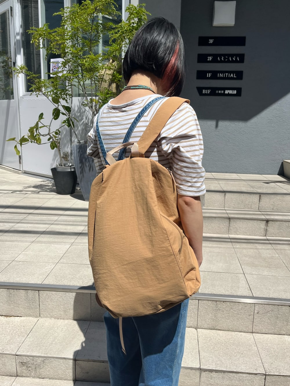 ベージュ系のバックパック/リュック、ホワイト系のスニーカーを着用したレディースの春コーディネートの3枚目の写真