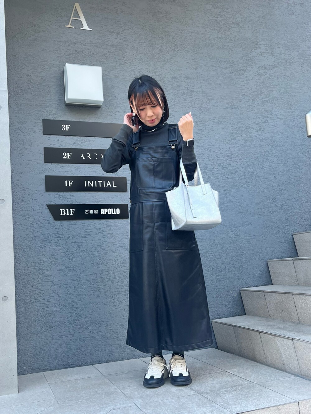 シルバー系のトートバッグ、ブラック系のTシャツ/カットソー、ブラック系のジャンパースカートを着用したレディースの冬コーディネートの2枚目の写真