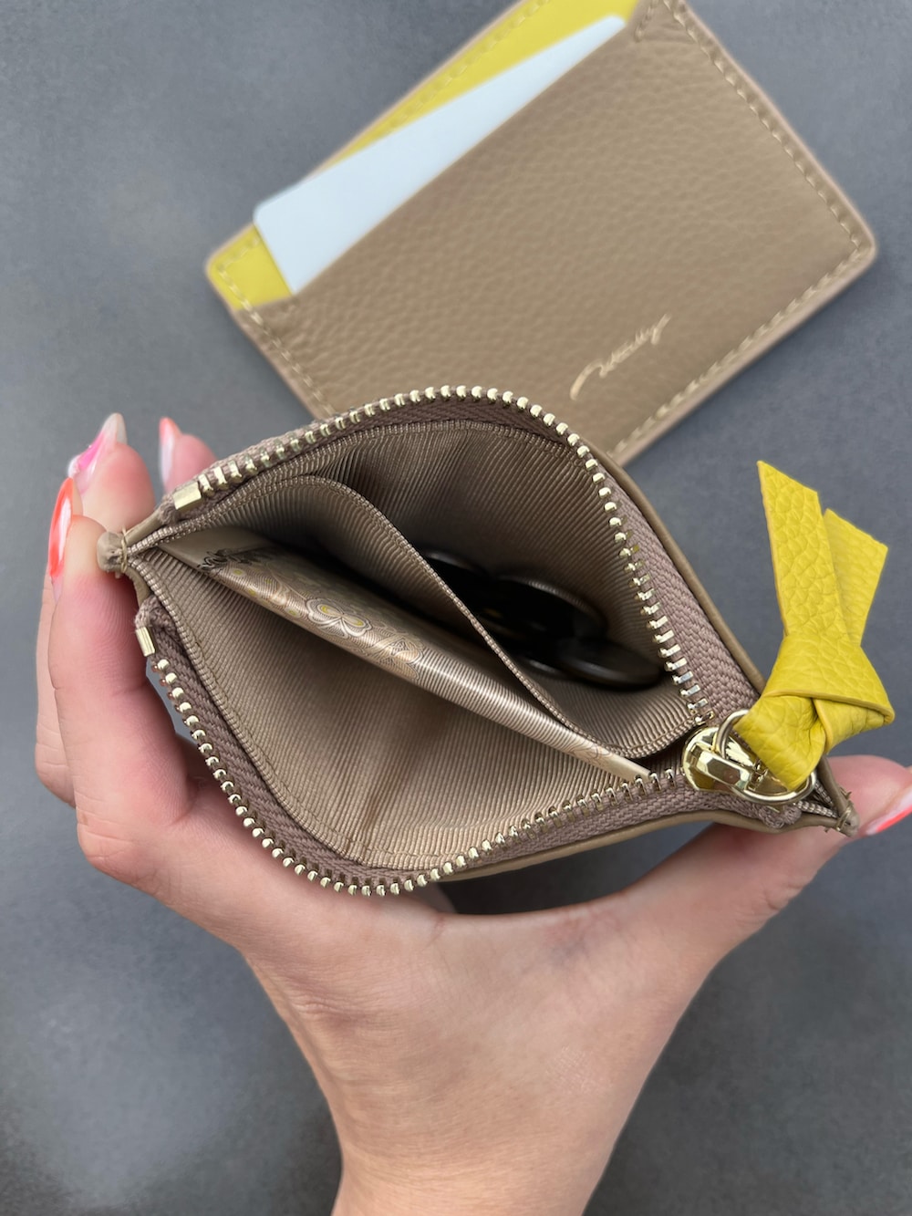 ブラック系のショルダーバッグ、イエロー系のカードケース、イエロー系のコインケースを着用したレディースの春コーディネートの2枚目の写真