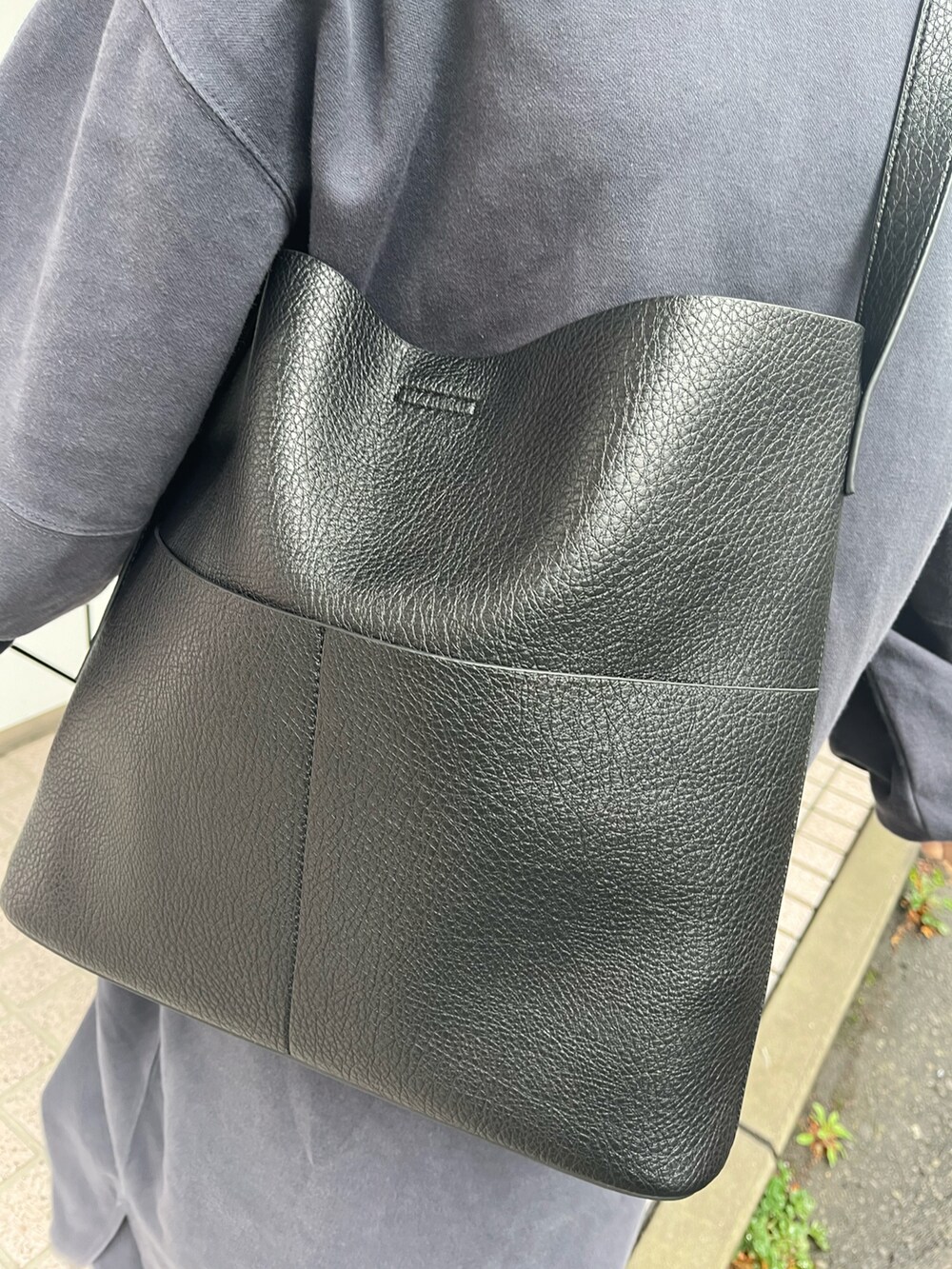 ブラック系のショルダーバッグ、ホワイト系のスニーカー、ブルー系のワンピースを着用したレディースの冬コーディネートの2枚目の写真