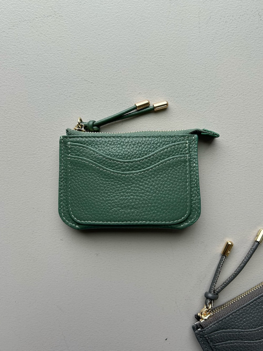 グリーン系の財布、ブラック系のポーチ、ブルー系のポーチを着用したレディースの春コーディネートの4枚目の写真