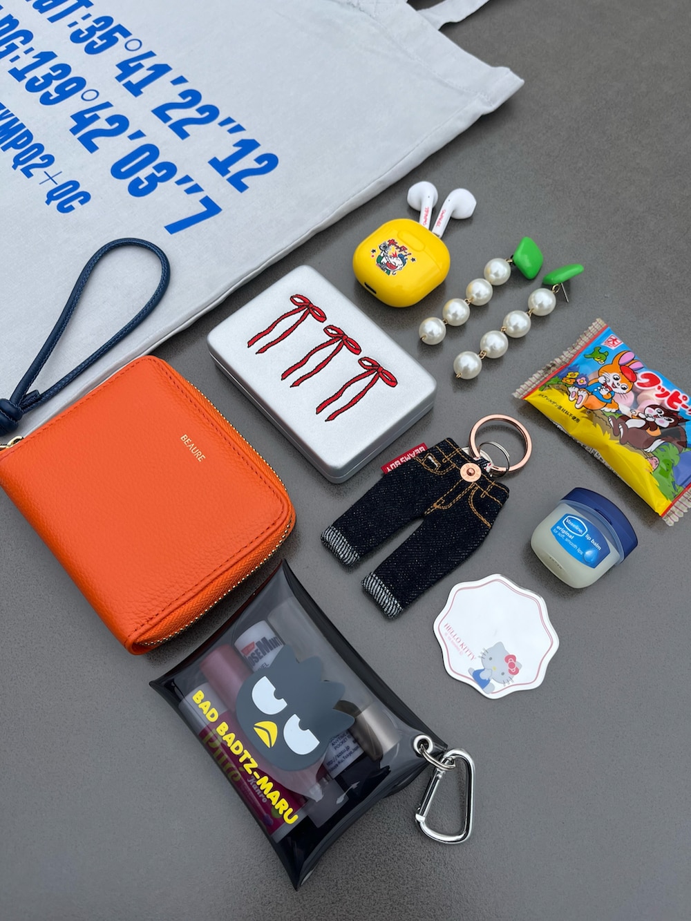 オレンジ系の財布、シルバー系のポーチ、その他のボディケア/ボディクリームを着用したレディースの春コーディネートの2枚目の写真