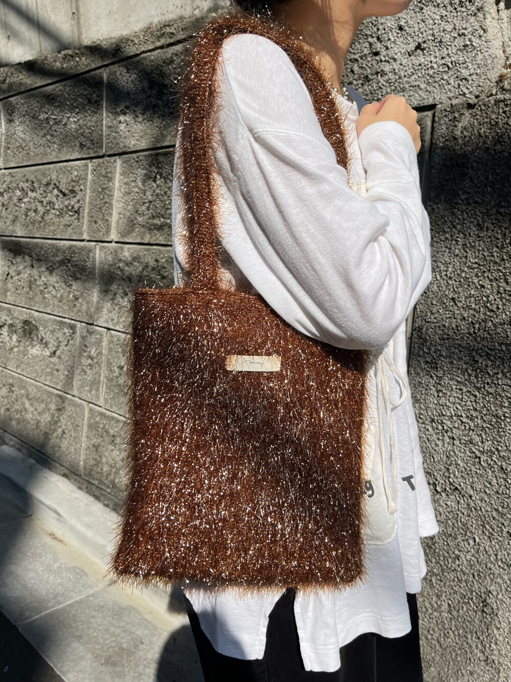 ブラウン系のトートバッグ、ホワイト系のTシャツ/カットソーを着用したレディースの秋コーディネートの3枚目の写真