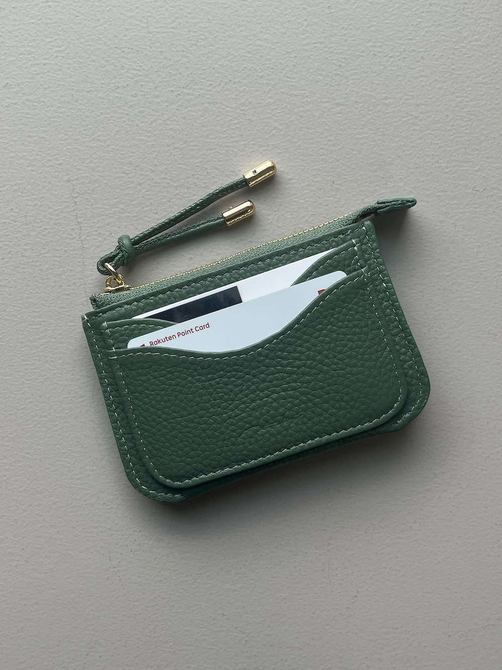 イエロー系のポーチ、グリーン系の財布、ホワイト系のチャームを着用したレディースの秋コーディネートの3枚目の写真