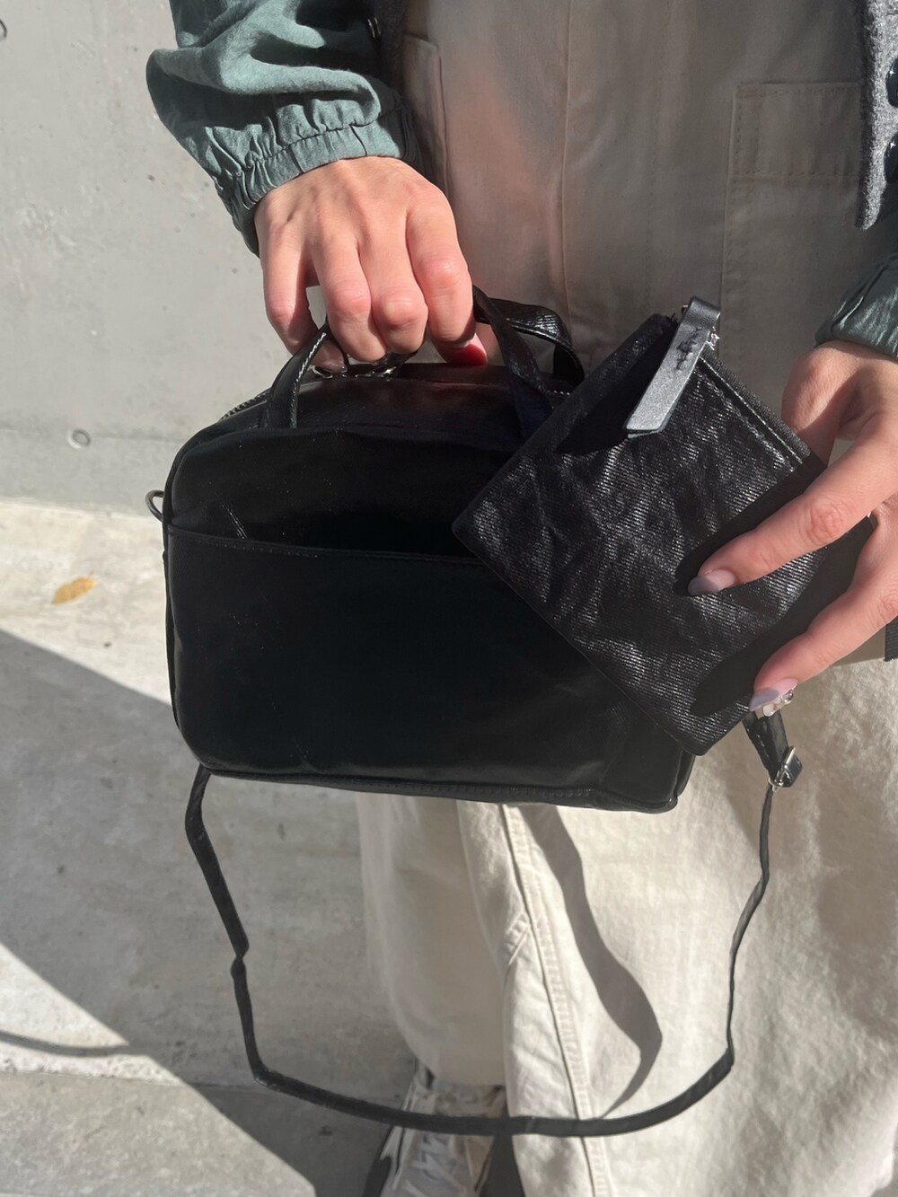 ブラック系のボストンバッグ、ベージュ系のスカート、ホワイト系のスニーカーを着用したレディースの秋コーディネートの2枚目の写真