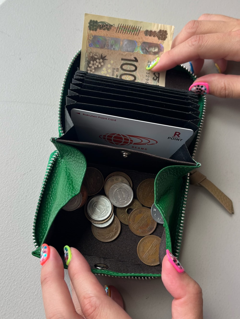 グリーン系の財布、ブルー系のポーチ、シルバー系のチャームを着用したレディースの夏コーディネートの5枚目の写真