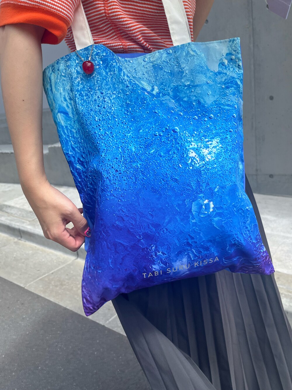 ブルー系のトートバッグ、ホワイト系のスニーカー、ブルー系の折りたたみ傘を着用したレディースの夏コーディネートの4枚目の写真