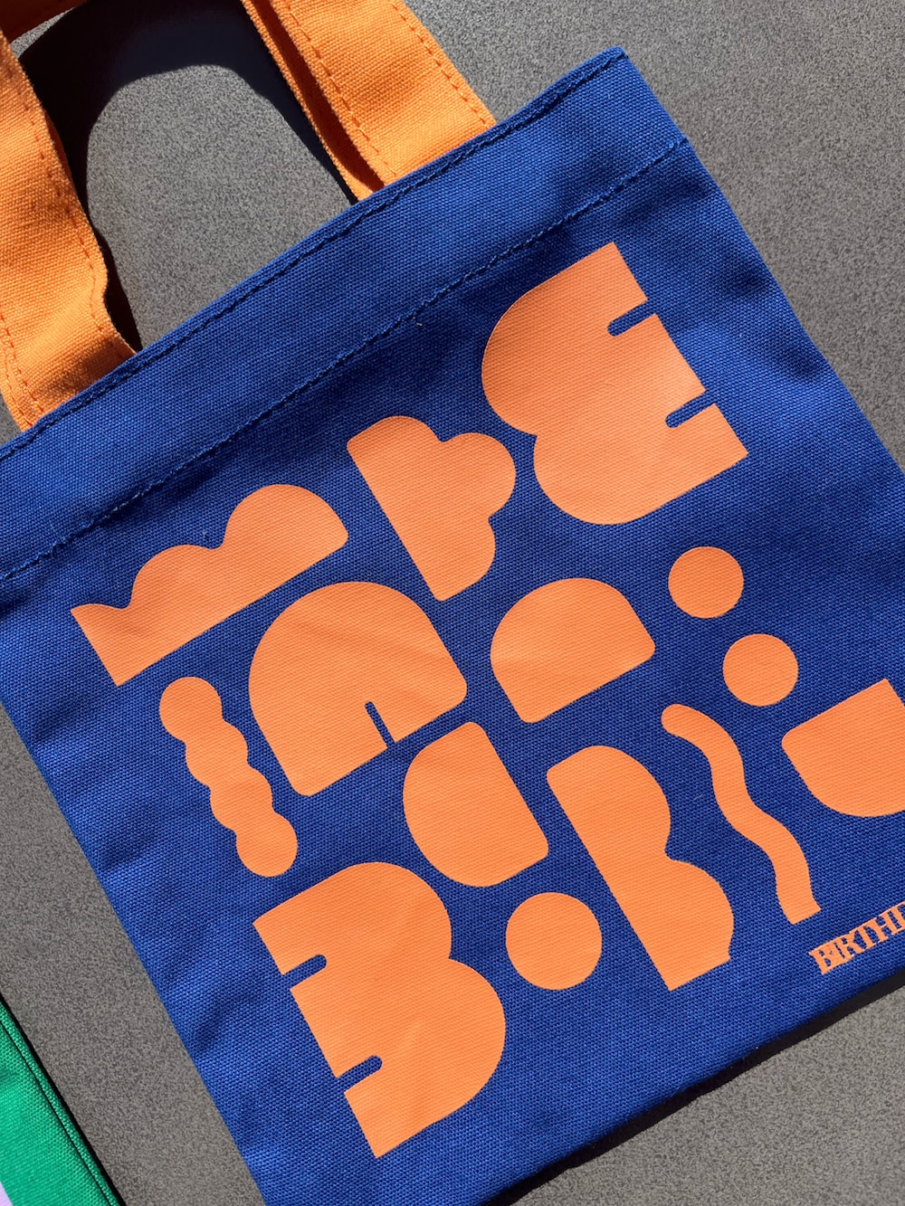 オレンジ系のトートバッグ、ピンク系のチャームを着用したレディースの春コーディネートの5枚目の写真