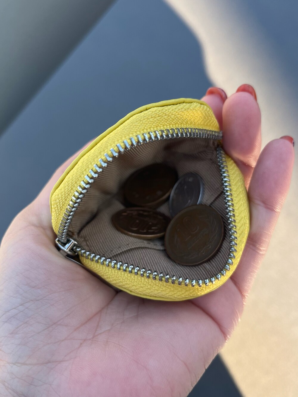 イエロー系のコインケース、パープル系のポーチ、グレー系のヘッドフォン/イヤホンを着用したレディースの冬コーディネートの2枚目の写真