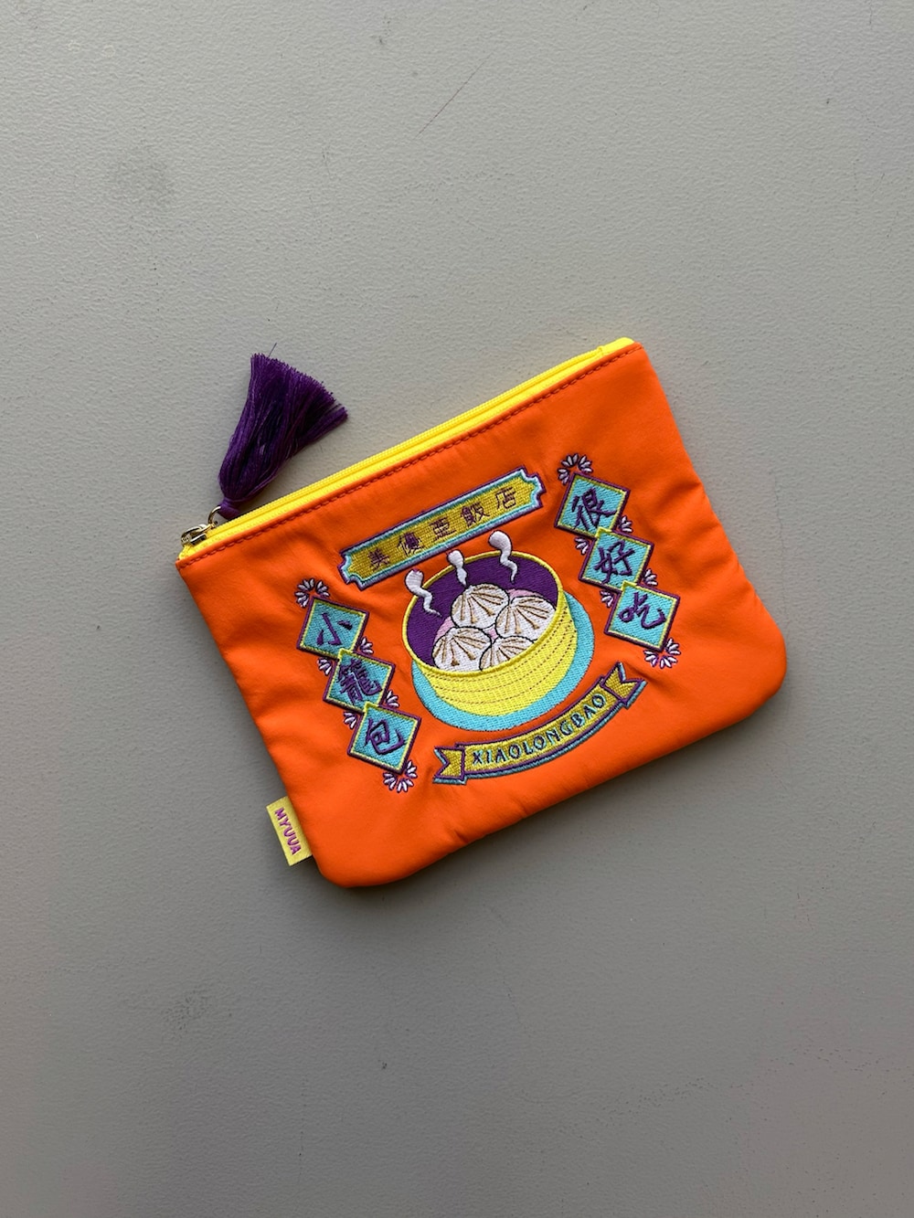 オレンジ系のポーチ、ホワイト系のチャーム、グレー系のポーチを着用したレディースの春コーディネートの2枚目の写真