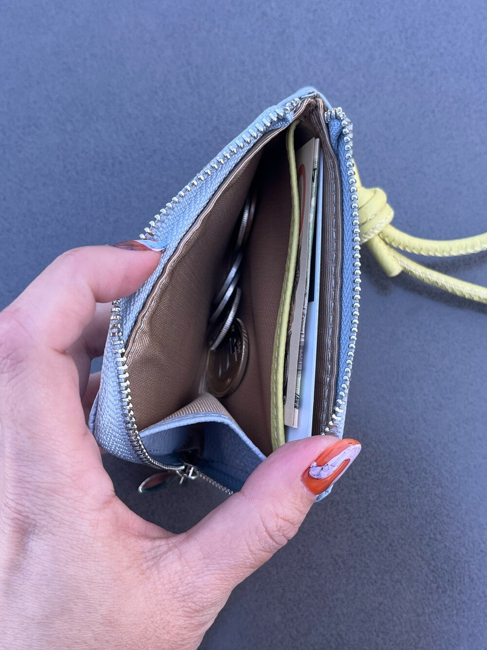 パープル系のポーチ、ベージュ系の財布、ブルー系の財布を着用したレディースの春コーディネートの3枚目の写真