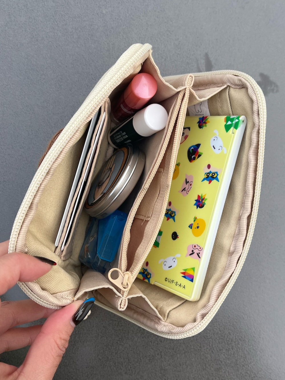 グリーン系のトートバッグ、ベージュ系のトラベルグッズ、グレー系のヘッドフォン/イヤホンを着用したレディースの冬コーディネートの4枚目の写真