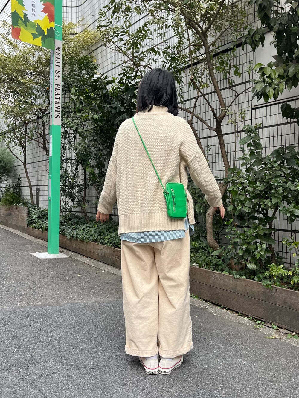 グリーン系のショルダーバッグ、ホワイト系のスニーカー、ベージュ系のニット/セーターを着用したレディースの冬コーディネートの2枚目の写真