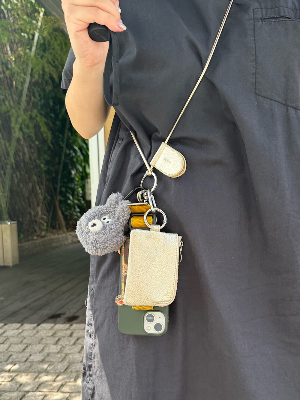 ブラック系のドレスシューズ、ブラック系のワンピース、ゴールド系のパスケースを着用したレディースの夏コーディネートの2枚目の写真